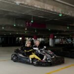 Elderly women enjoy a thrilling go-kart ride in an indoor parking area, showcasing their adventurous spirit.