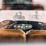Classic vintage car interior with focus on dashboard and blurred motorcycles outside.