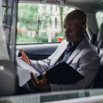 African American businessman reading documents inside a car, demonstrating focus and professionalism.