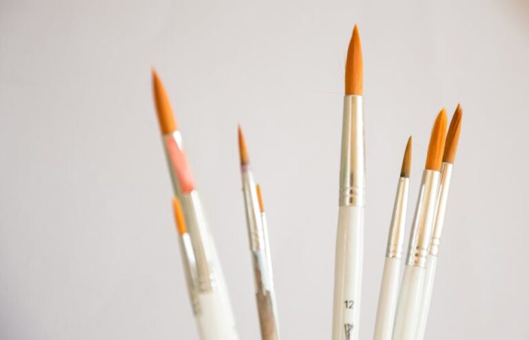 Assorted thin paintbrushes displayed on a neutral white background, ideal for art projects.