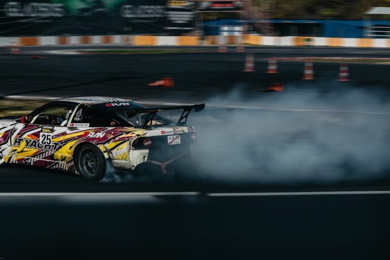 Dynamic image of a car drifting on a racing track with smoke trailing behind.