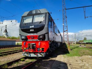 A modern freight train parked on railway tracks under a clear blue sky.
