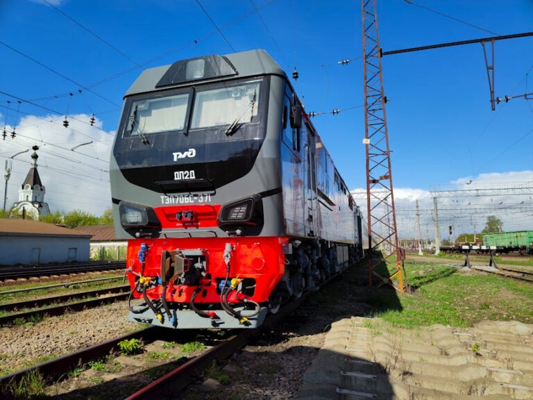 A modern freight train parked on railway tracks under a clear blue sky.