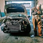 Mechanic repairing car in an auto workshop with the hood open showcasing the engine.