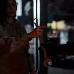 A mechanic handing over a wrench in a dimly lit garage workshop, creating a moody atmosphere.