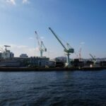 View of cranes at Kobe port under a clear blue sky, showcasing Japan's industrial capabilities.