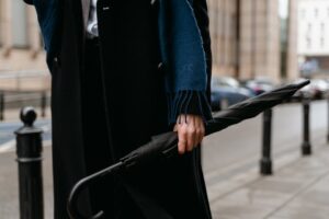 A stylish individual holding an umbrella on a city street, embodying urban fashion and sophistication.