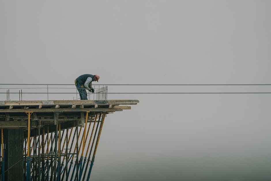 Worker on construction site framework against a cloudy sky in Denizli, Türkiye.