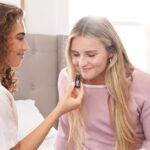 Two young women enjoying aromatherapy in a cozy bedroom setting, highlighting relaxation.