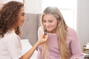 Two young women enjoying aromatherapy in a cozy bedroom setting, highlighting relaxation.