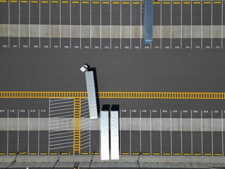 An aerial view of a large parking lot with lined spaces and semi-trucks.