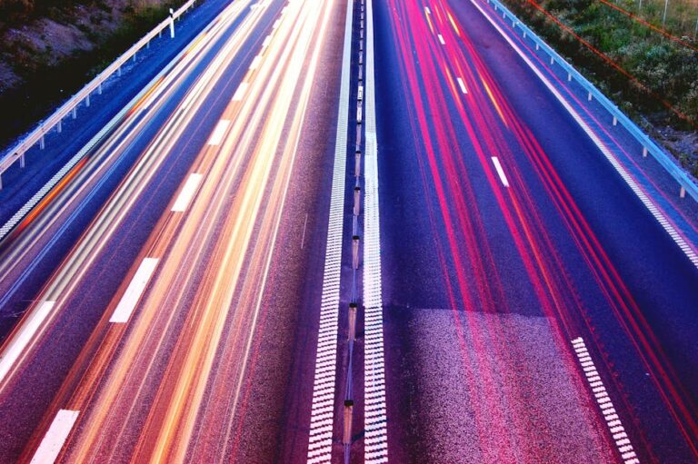 Long exposure capture of vibrant light trails on a highway at dusk, showcasing motion and speed.