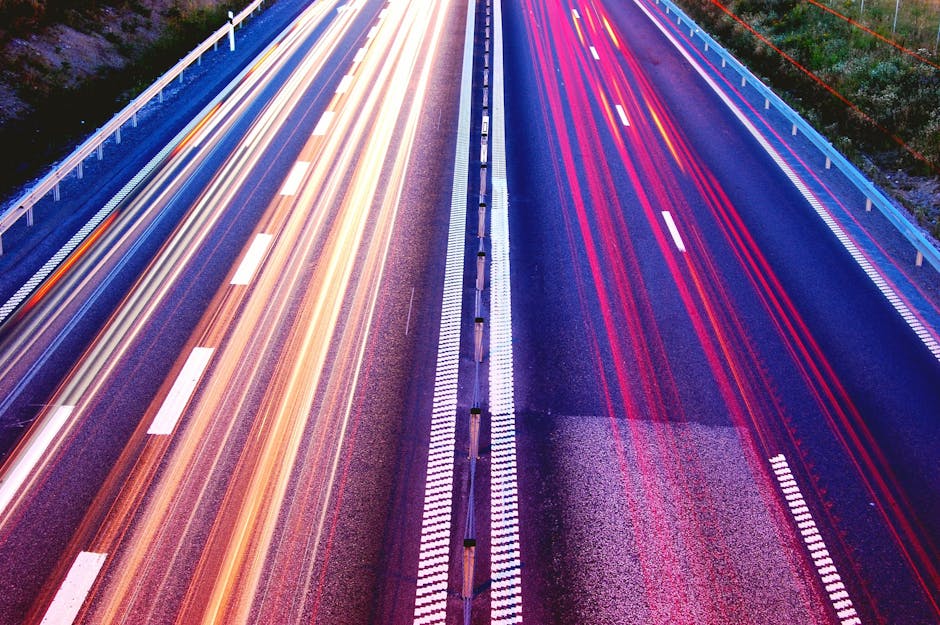 Long exposure capture of vibrant light trails on a highway at dusk, showcasing motion and speed.