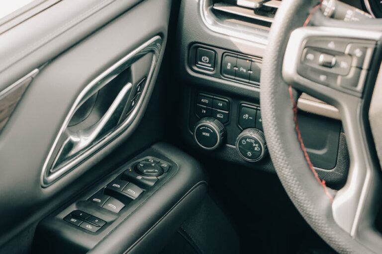 Close-up of a modern car interior showcasing controls, steering wheel, and door handle.